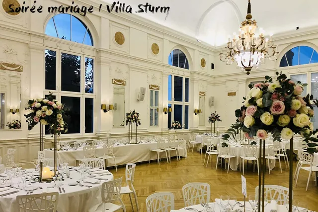 Tables et bouquets installés dans la salle de réception de la Villa Sturm